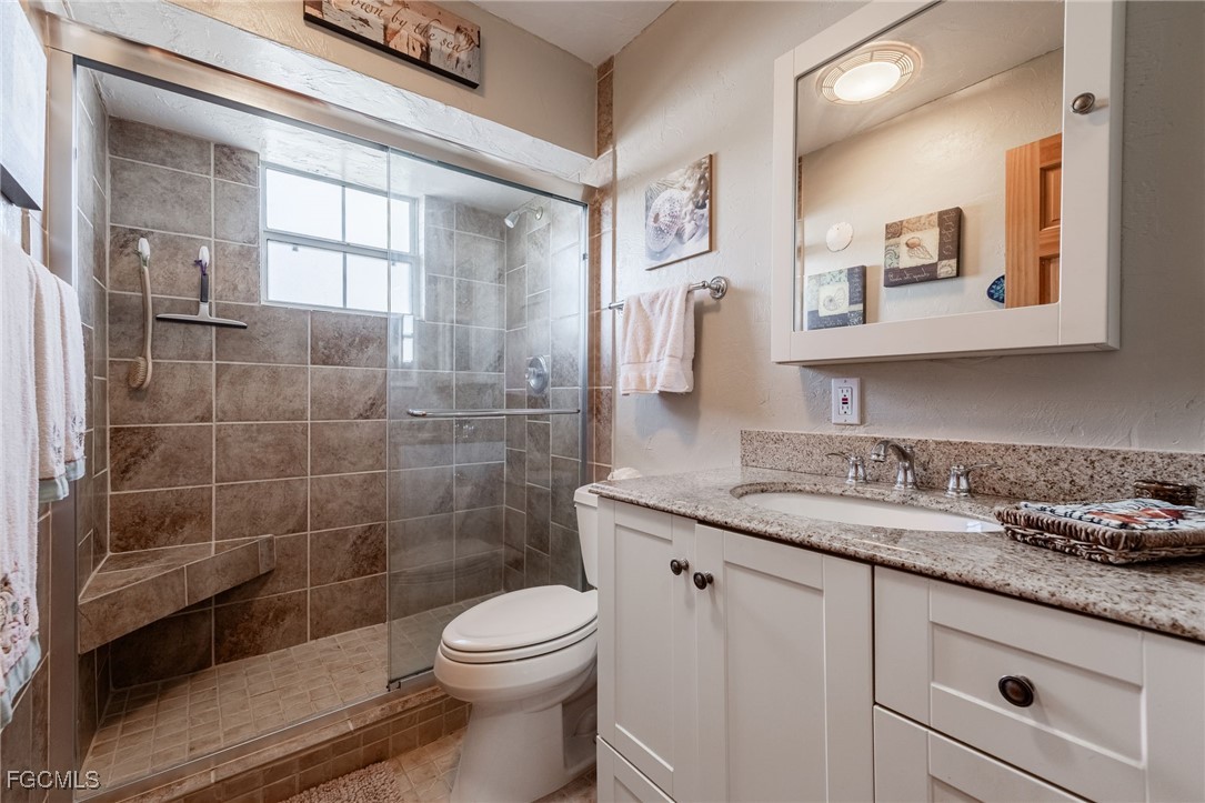 3374 York Road St. James City, FL 33956 - Photo 26 of 49 a bathroom with a granite countertop sink a toilet a mirror and shower