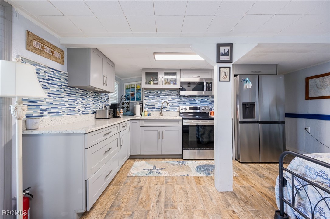 3374 York Road St. James City, FL 33956 - Photo 31 of 49 a kitchen with stainless steel appliances granite countertop a refrigerator a sink dishwasher a stove and white countertops with wooden floor