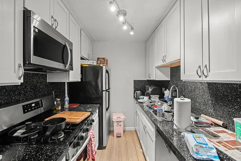 a kitchen with stainless steel appliances a stove a sink dishwasher and microwave with wooden floor