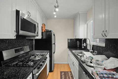 a kitchen with stainless steel appliances a stove a microwave a sink and cabinets