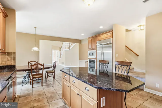 a dining hall with stainless steel appliances granite countertop a stove a sink a dining table and chairs