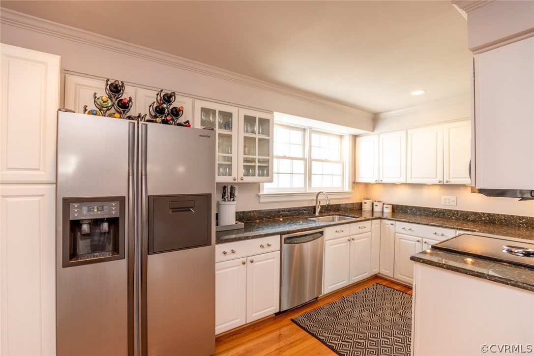 The kitchen has hardwood floors, white cabinetry,