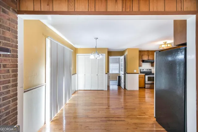 a view of dining room with kitchen island stainless steel appliances a refrigerator stove oven with white cabinets and wooden floor