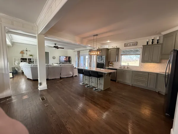 a living room with furniture and a dining table with wooden floor
