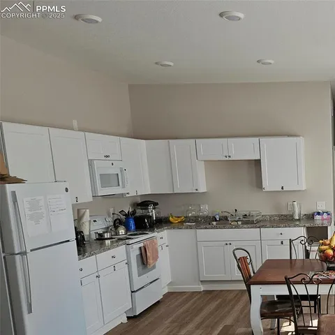 a kitchen with granite countertop white cabinets and white appliances