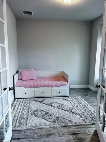 a view of a bedroom with a bed and wooden floor
