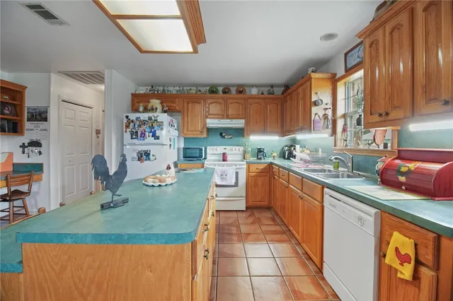 a kitchen with stainless steel appliances granite countertop a sink dishwasher stove top oven a dining table and chairs with wooden floor