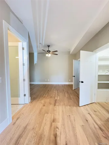 a view of empty room with wooden floor and fan