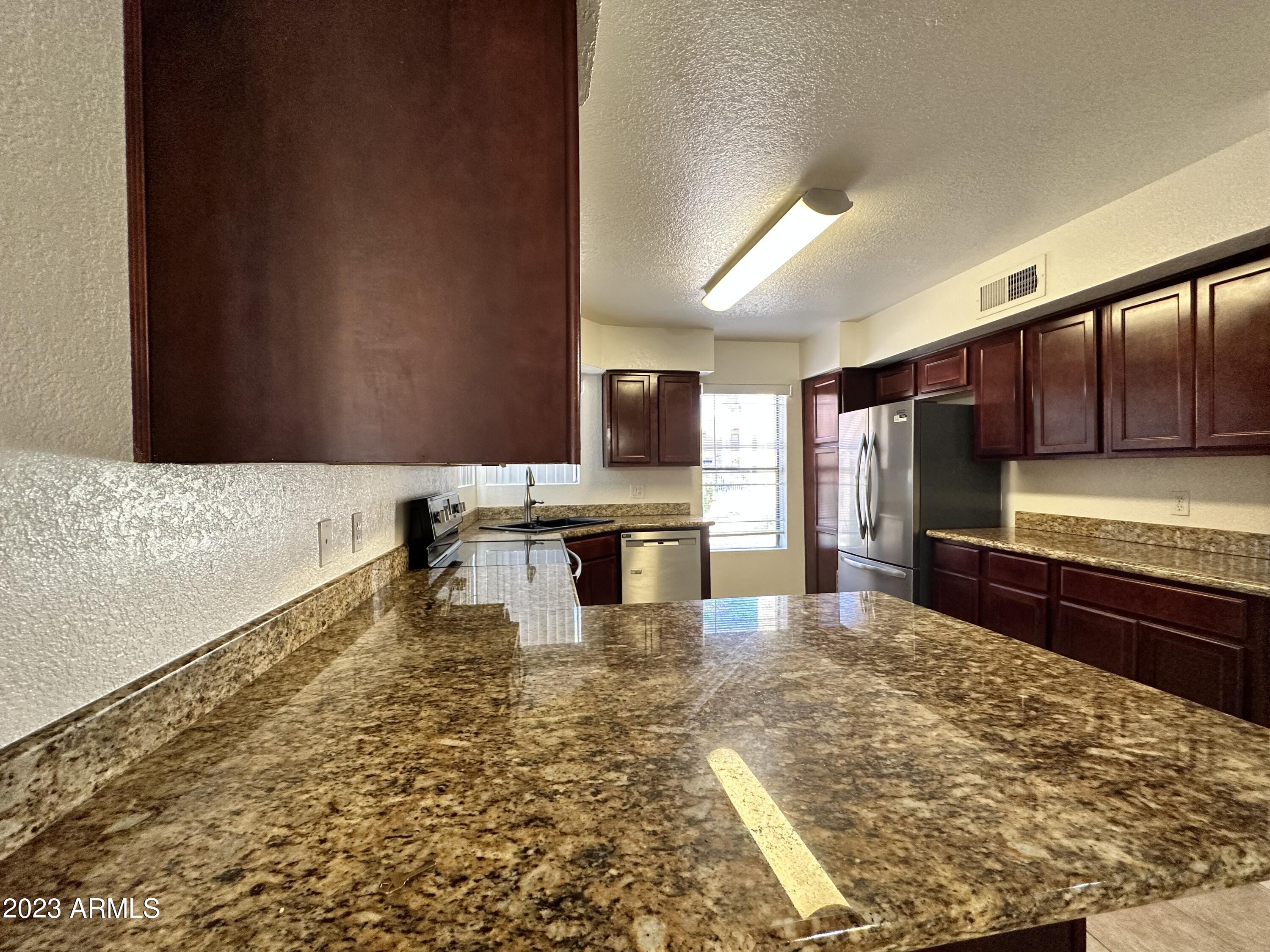 8787 East Mountain View Road, Unit 1103 Scottsdale, AZ 85258 - Photo 15 of 38 a large kitchen with kitchen island granite countertop a stove a sink and a microwave