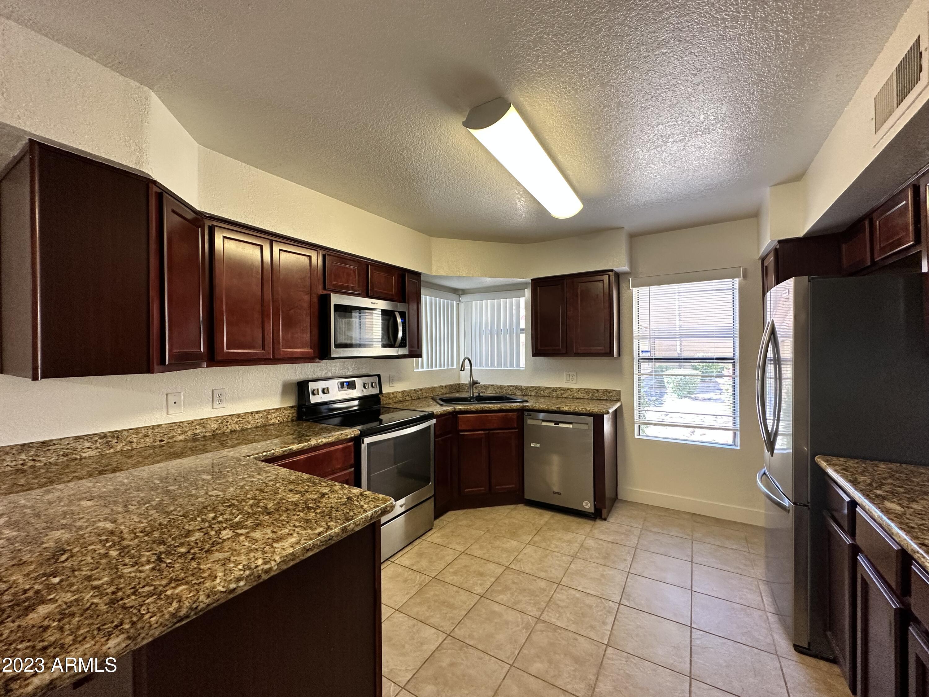 8787 East Mountain View Road, Unit 1103 Scottsdale, AZ 85258 - Photo 16 of 38 a kitchen with stainless steel appliances granite countertop refrigerator stove microwave and sink