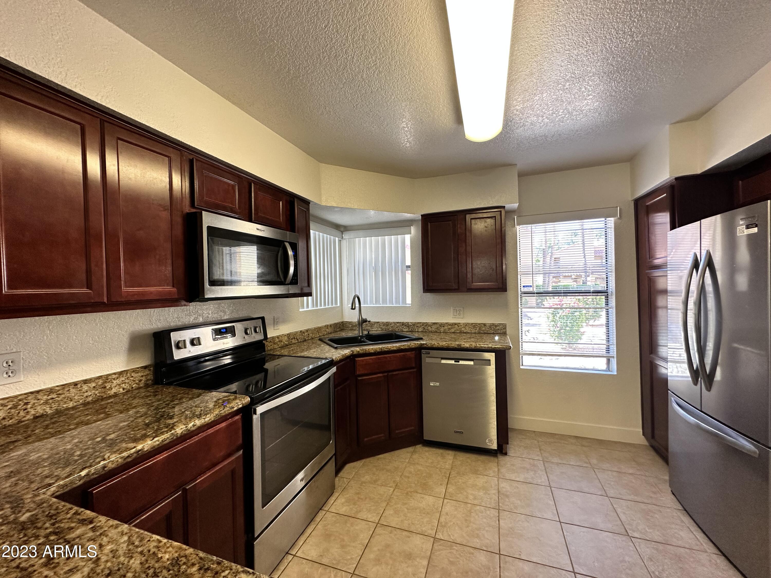 8787 East Mountain View Road, Unit 1103 Scottsdale, AZ 85258 - Photo 19 of 38 a kitchen with stainless steel appliances granite countertop a stove microwave and sink
