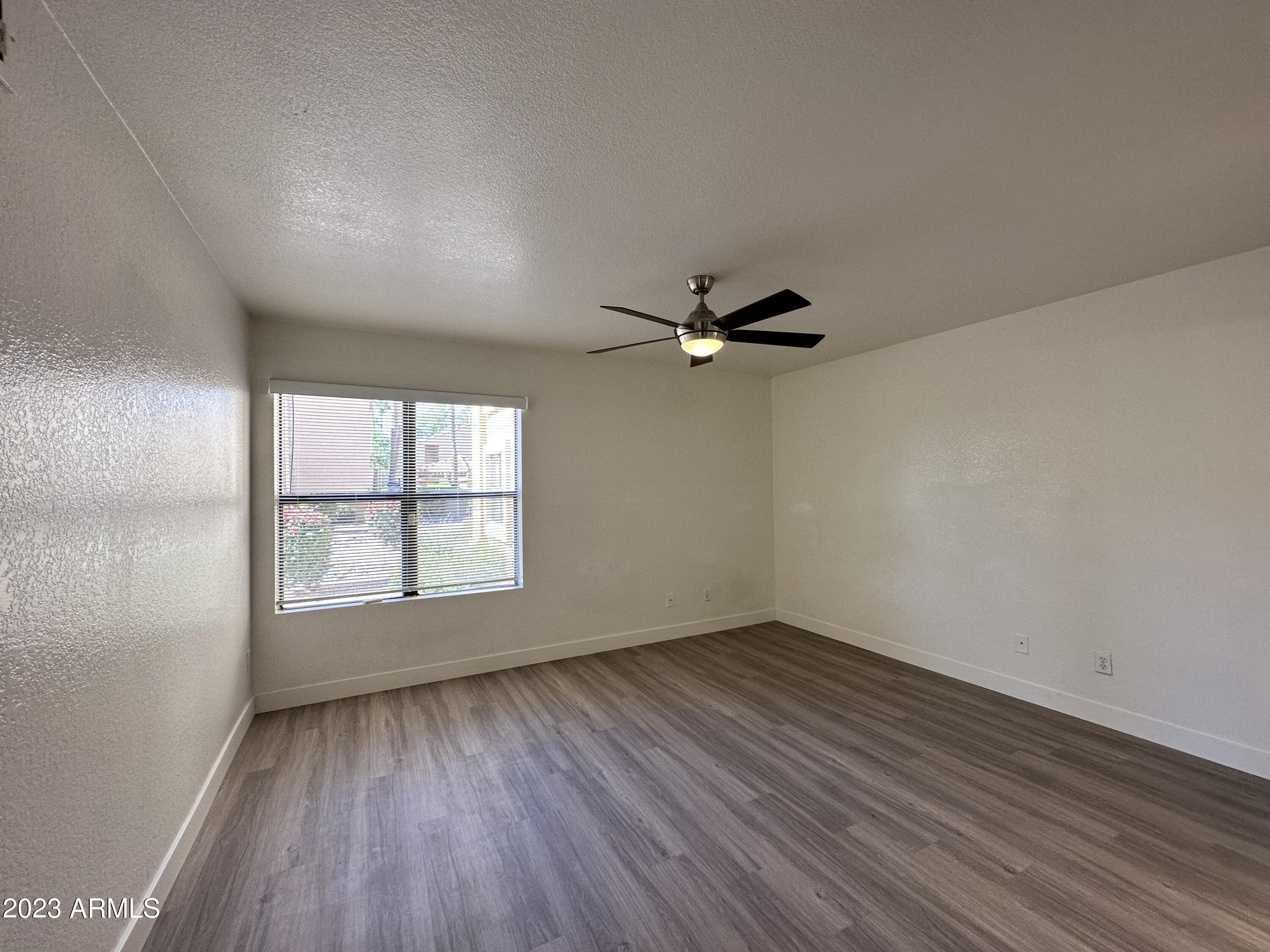 8787 East Mountain View Road, Unit 1103 Scottsdale, AZ 85258 - Photo 28 of 38 an empty room with wooden floor fan and windows