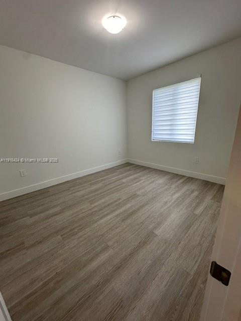 18975 Southwest 345th Terrace, Unit 18975 Homestead, FL 33034 - Photo 12 of 17 an empty room with wooden floor and windows