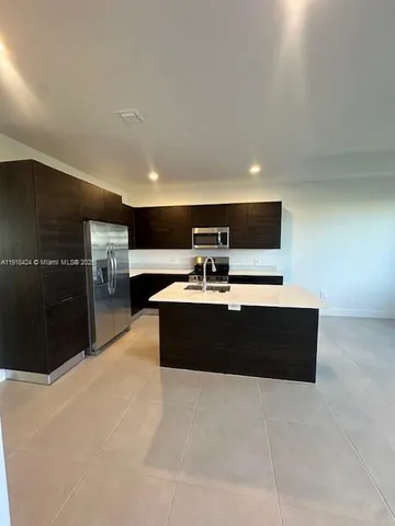 a living room with stainless steel appliances kitchen island furniture and a flat screen tv