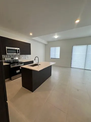a large kitchen with stainless steel appliances a sink dishwasher stove and cabinets