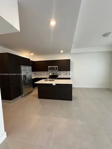 a large room with kitchen island a sink dishwasher stove and cabinets