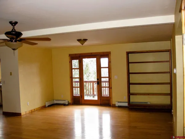 a view of an empty room with a window and wooden floor