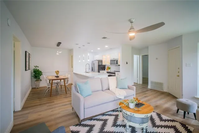 a living room with furniture and a dining table with wooden floor