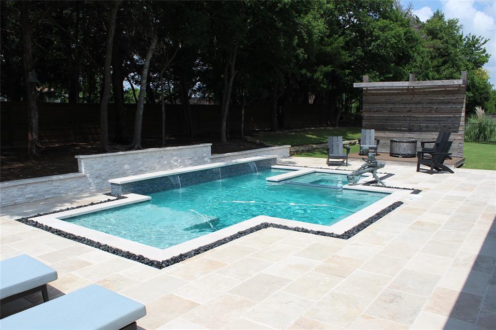 333 Renaissance Lane Heath, TX 75032 - Photo 7 of 35 Resort-style pool area featuring a geometric pool with a raised spa, stone tile patio, and a stacked stone water feature