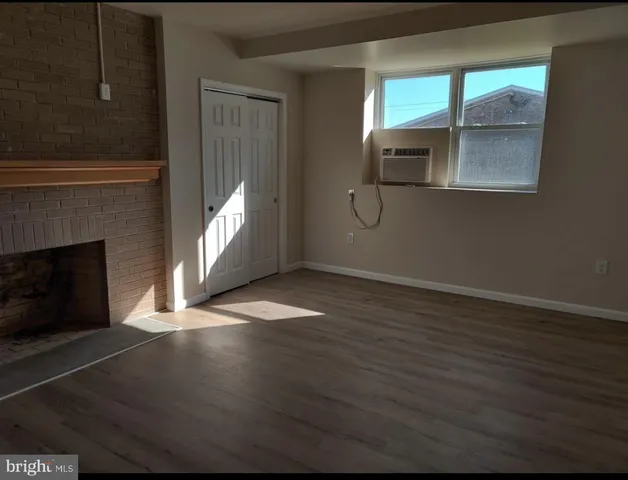 an empty room with wooden floor fireplace and windows
