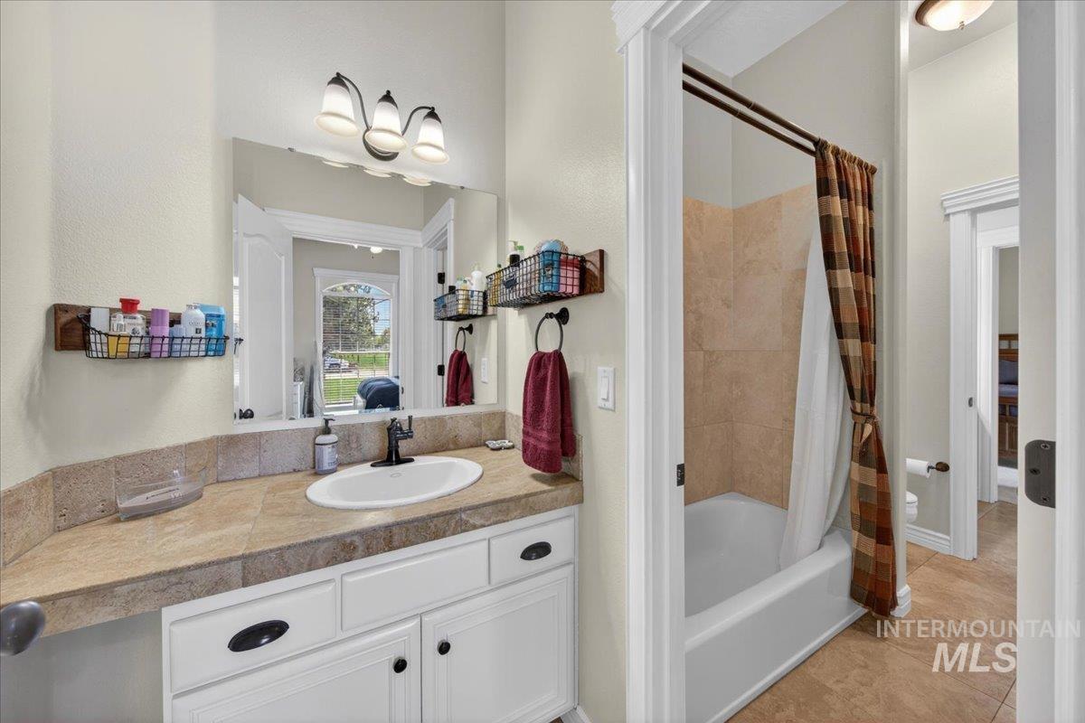 414 East Shafer View Drive Meridian, ID 83642 - Photo 28 of 50 Bathroom featuring a Jack & Jill style set up w/white vanity has dark hardware, tiled countertop, tiled tub/shower combo, tile flooring