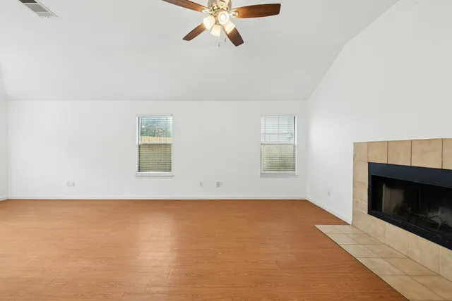 an empty room with windows and fireplace