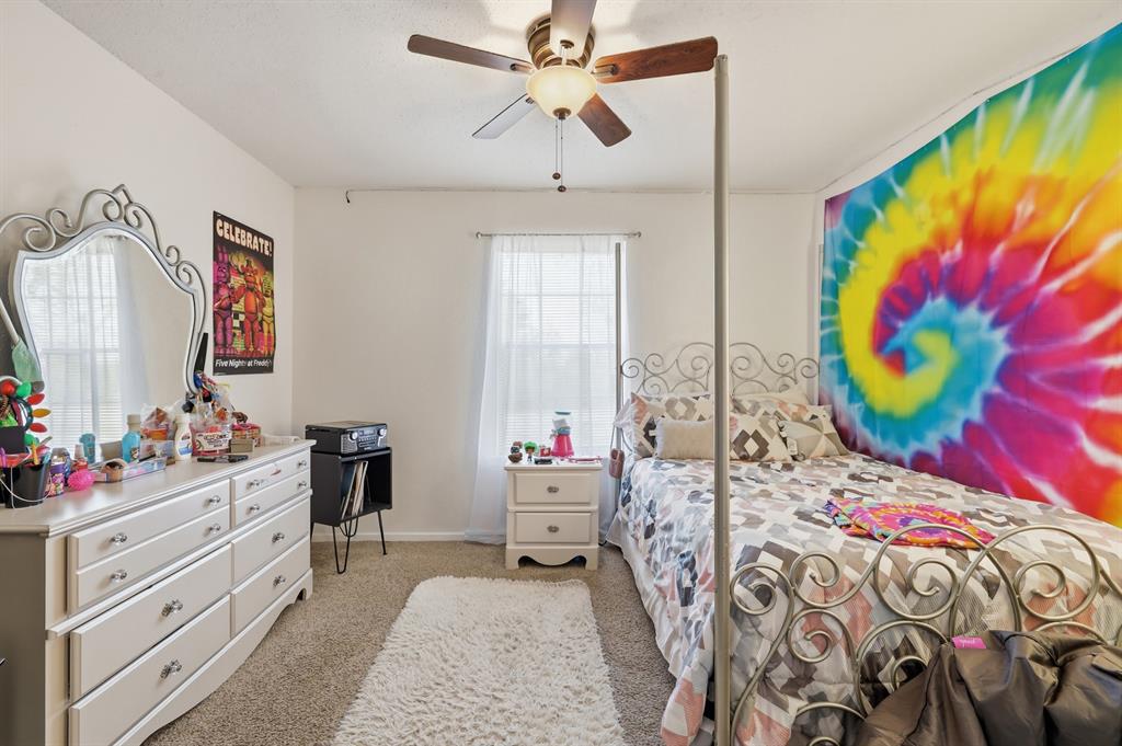 346 Meridian Street Gladewater, TX 75647 - Photo 13 of 28 a bedroom with a bed a dresser and a window