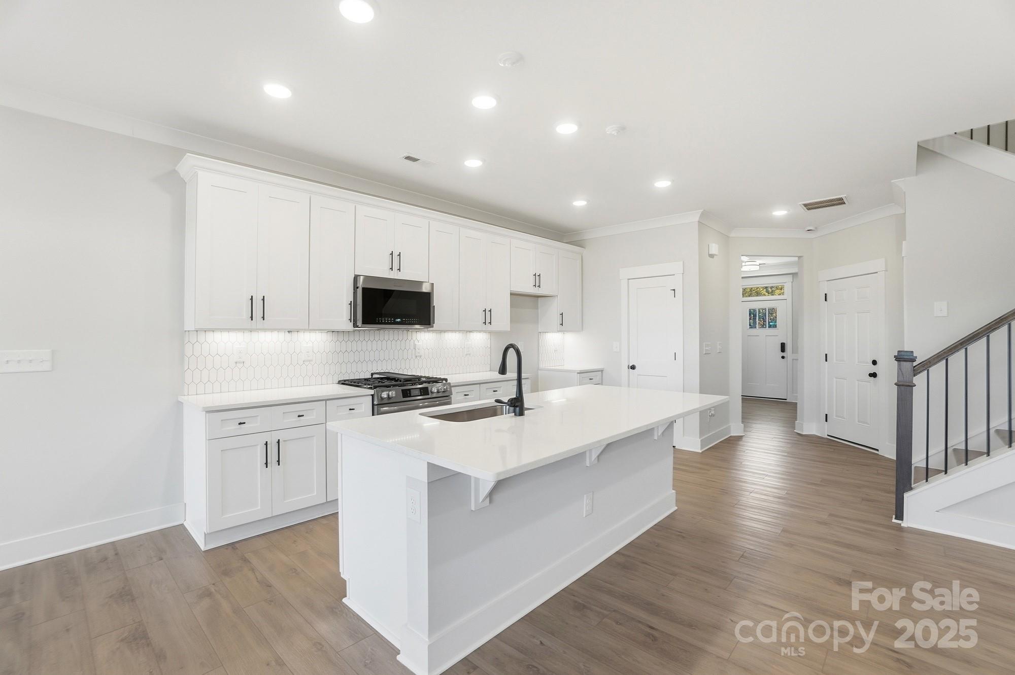 406 Limelight Road Waxhaw, NC 28173 - Photo 13 of 48 a large kitchen with stainless steel appliances granite countertop a stove a sink a refrigerator and white cabinets with wooden floor