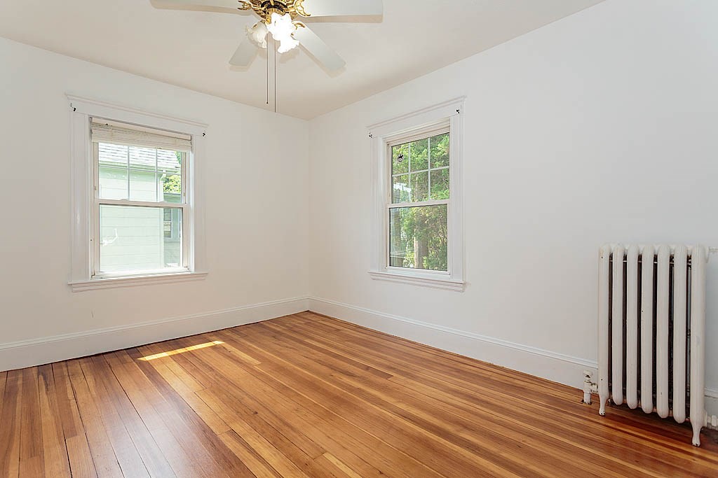 37 Huntington Road Milton, MA 02186 - Photo 28 of 35 an empty room with wooden floor chandelier fan and windows