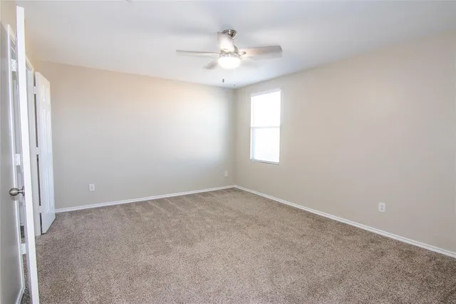 an empty room with windows and chandelier fan