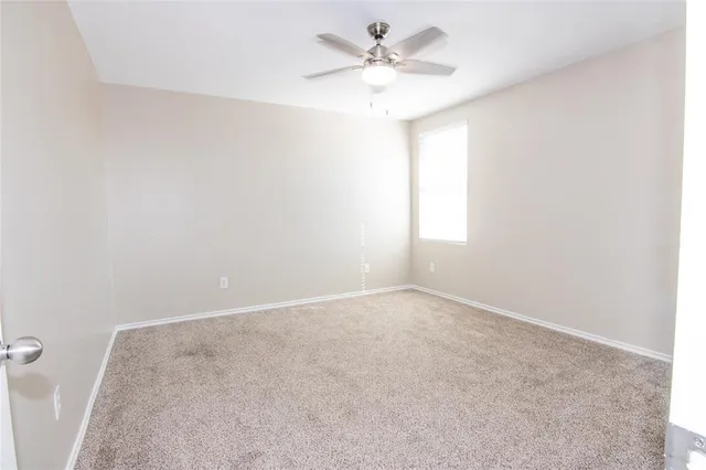 an empty room with a window and a fan