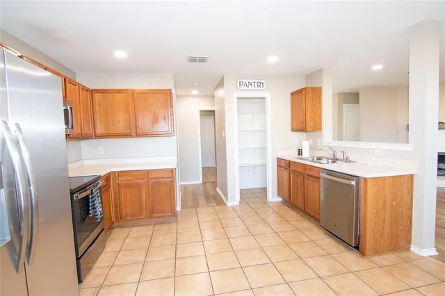 a large kitchen with stainless steel appliances kitchen island granite countertop a refrigerator and a sink