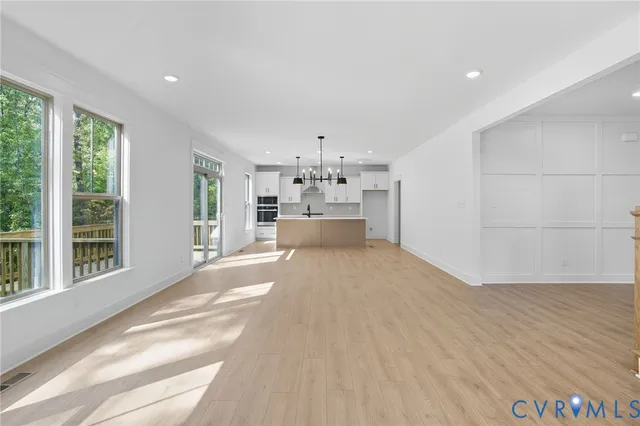 an empty room with windows fireplace and wooden floor
