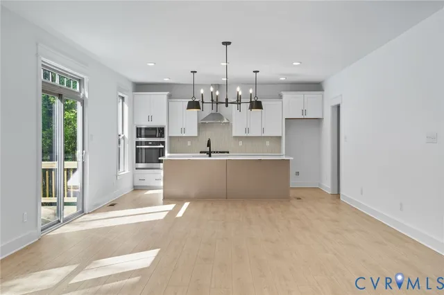 a kitchen with stainless steel appliances granite countertop a sink a stove and a wooden floors