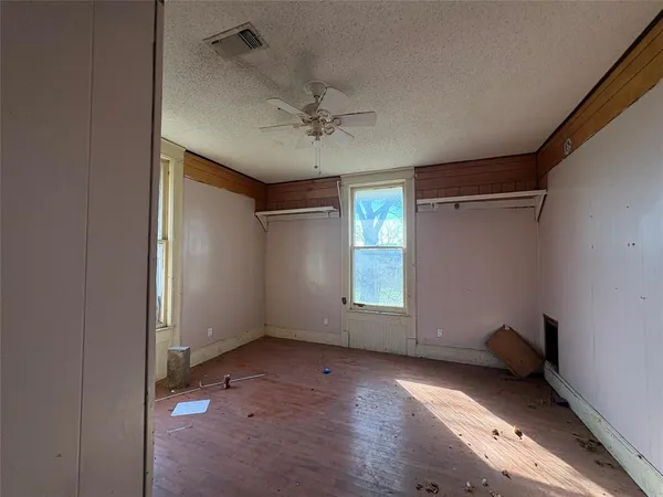 an empty room with windows and chandelier fan