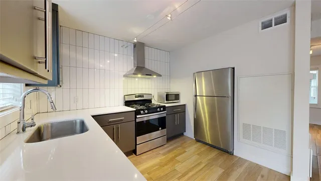 a kitchen with stainless steel appliances a refrigerator a sink a stove and cabinets