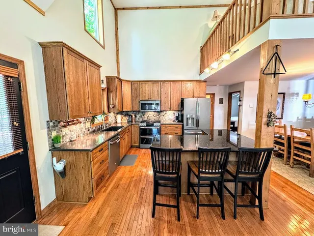 a kitchen with stainless steel appliances granite countertop a refrigerator a stove and a wooden cabinets
