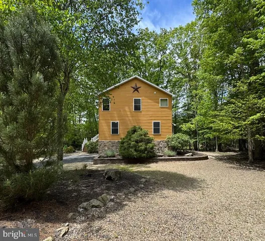 a view of a house with a yard and large trees