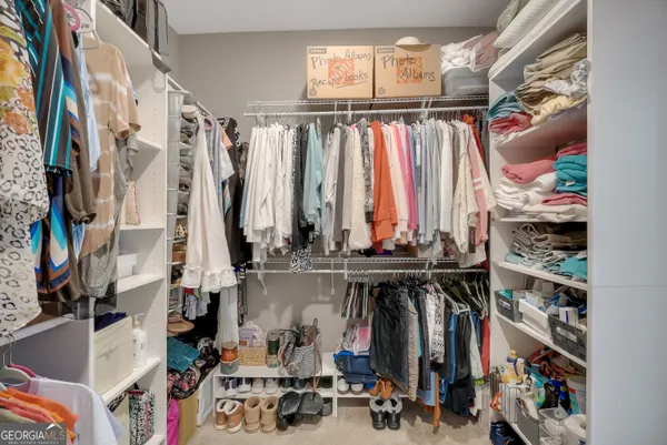 a view of walk in closet with clothes and shoes