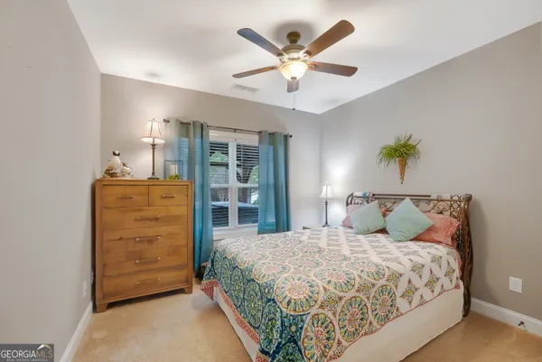 a bedroom with a bed a dresser and a chandelier
