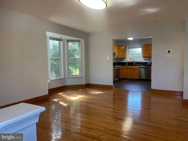 a view of a kitchen and an empty room with wooden floor