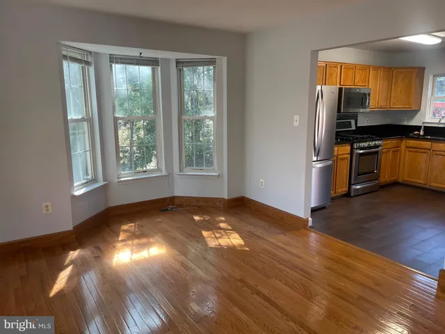 a view of an empty room with window and wooden floor