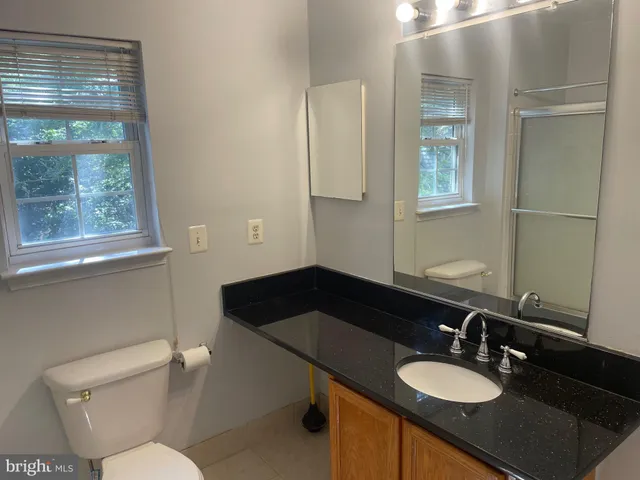 a bathroom with a granite countertop sink a mirror and a toilet