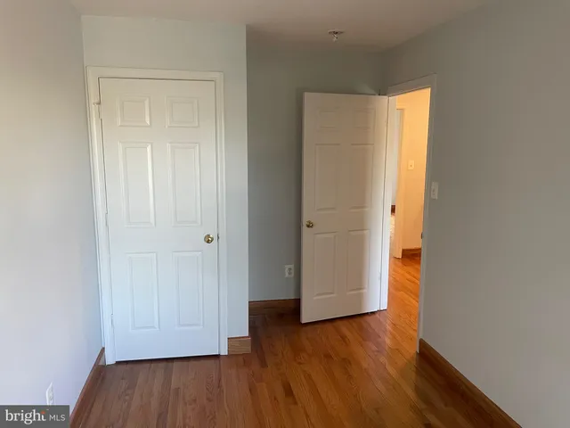 a view of an empty room with wooden floor and closet