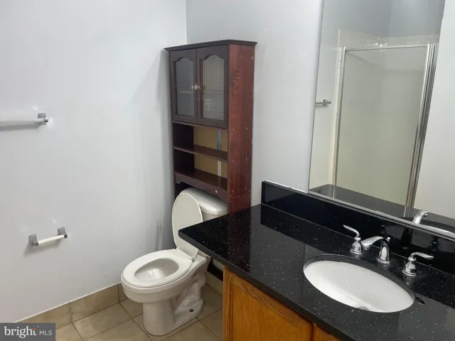a bathroom with a granite countertop toilet sink and mirror