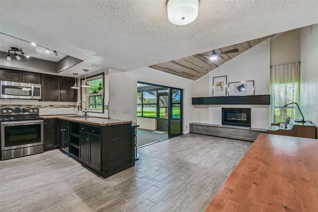 5319 Saddlebrook Way Wesley Chapel, FL 33543 - Photo 36 of 77 a kitchen with stainless steel appliances granite countertop a stove top oven a sink dishwasher a refrigerator and a fireplace with wooden floor