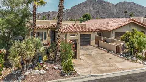 a view of a white house with large trees and plants