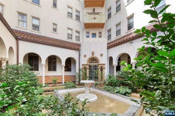 a front view of a multi story residential apartment building with a yard and large tree