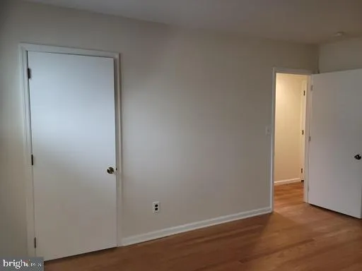 a view of an empty room with wooden floor and closet