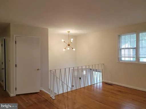 a view of a hallway with wooden floor and chandelier